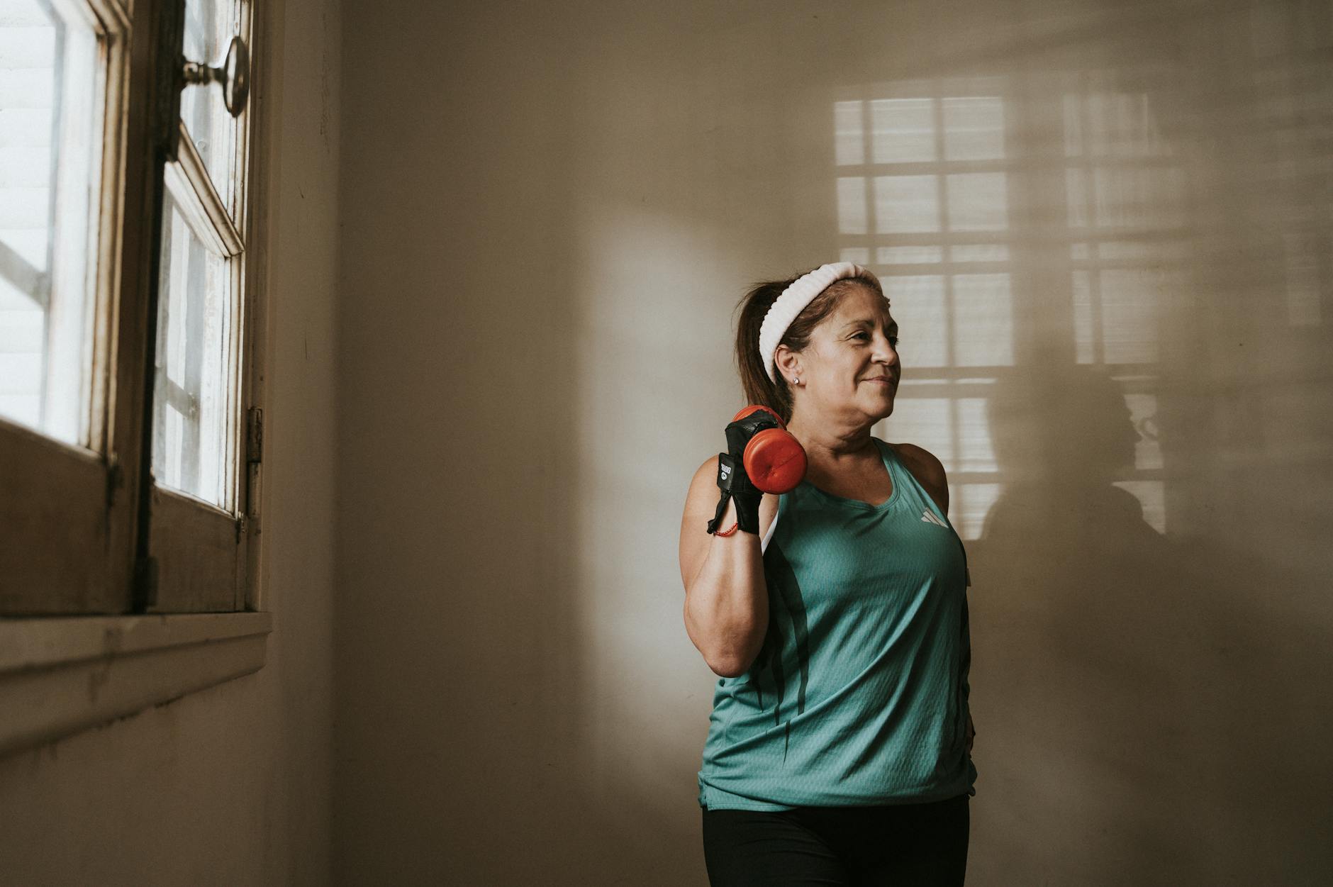 Kobieta w średnim wieku ćwiczy w domu z hantlem