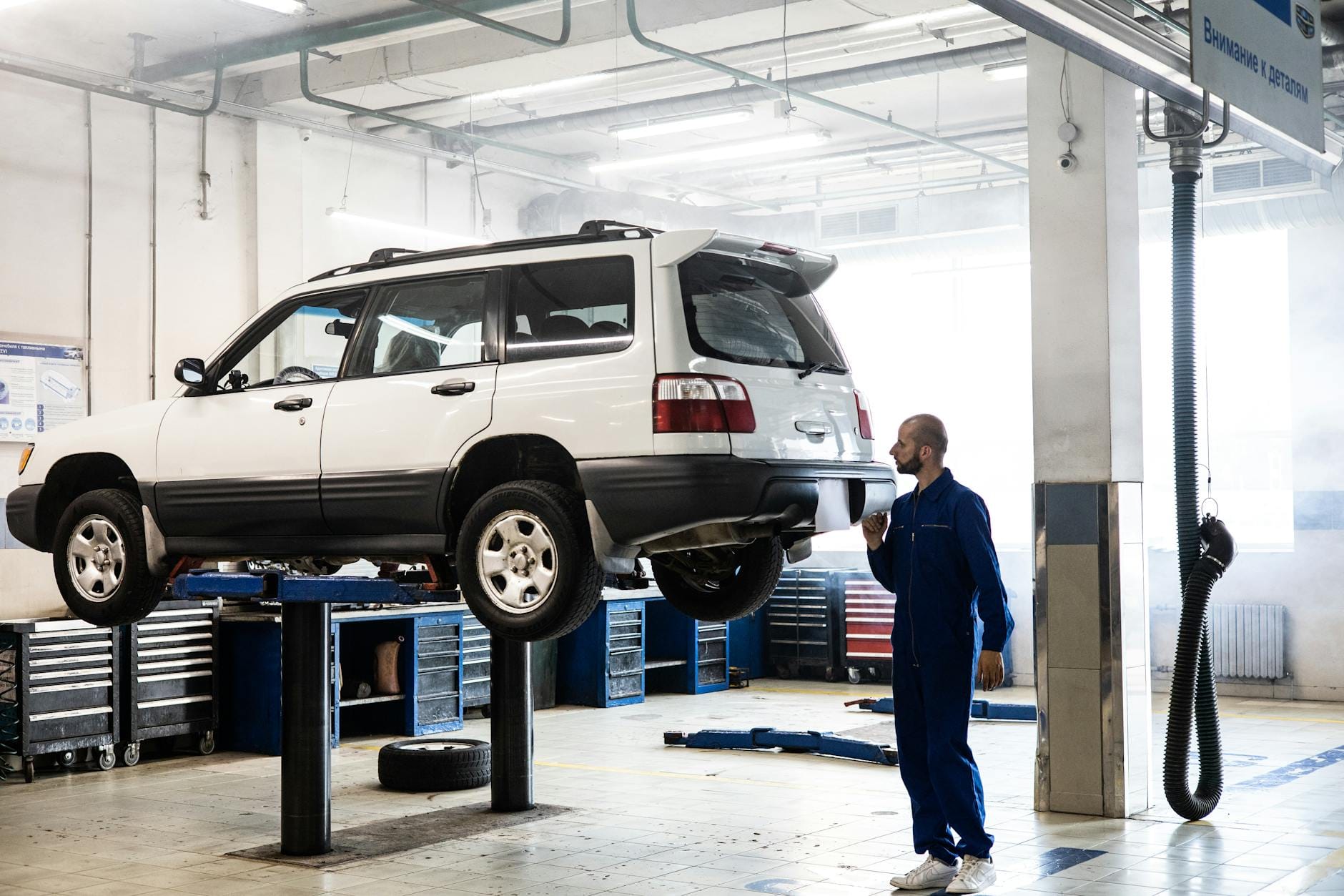 Mechanik ogląda zawieszone na podnośniku Volvo XC60 w warsztacie