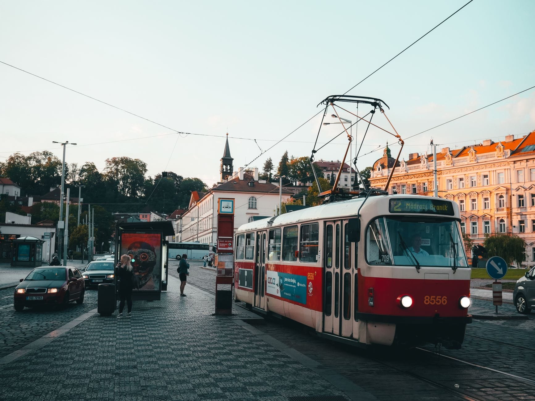 Zabytkowy tramwaj na brukowanej ulicy Pragi o zachodzie słońca